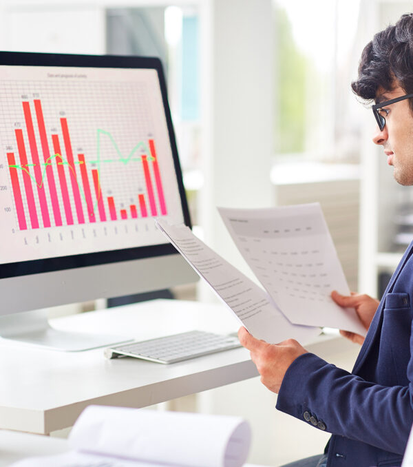 Paper analysis Businessman looking through papers by workplace and analyzing statistics